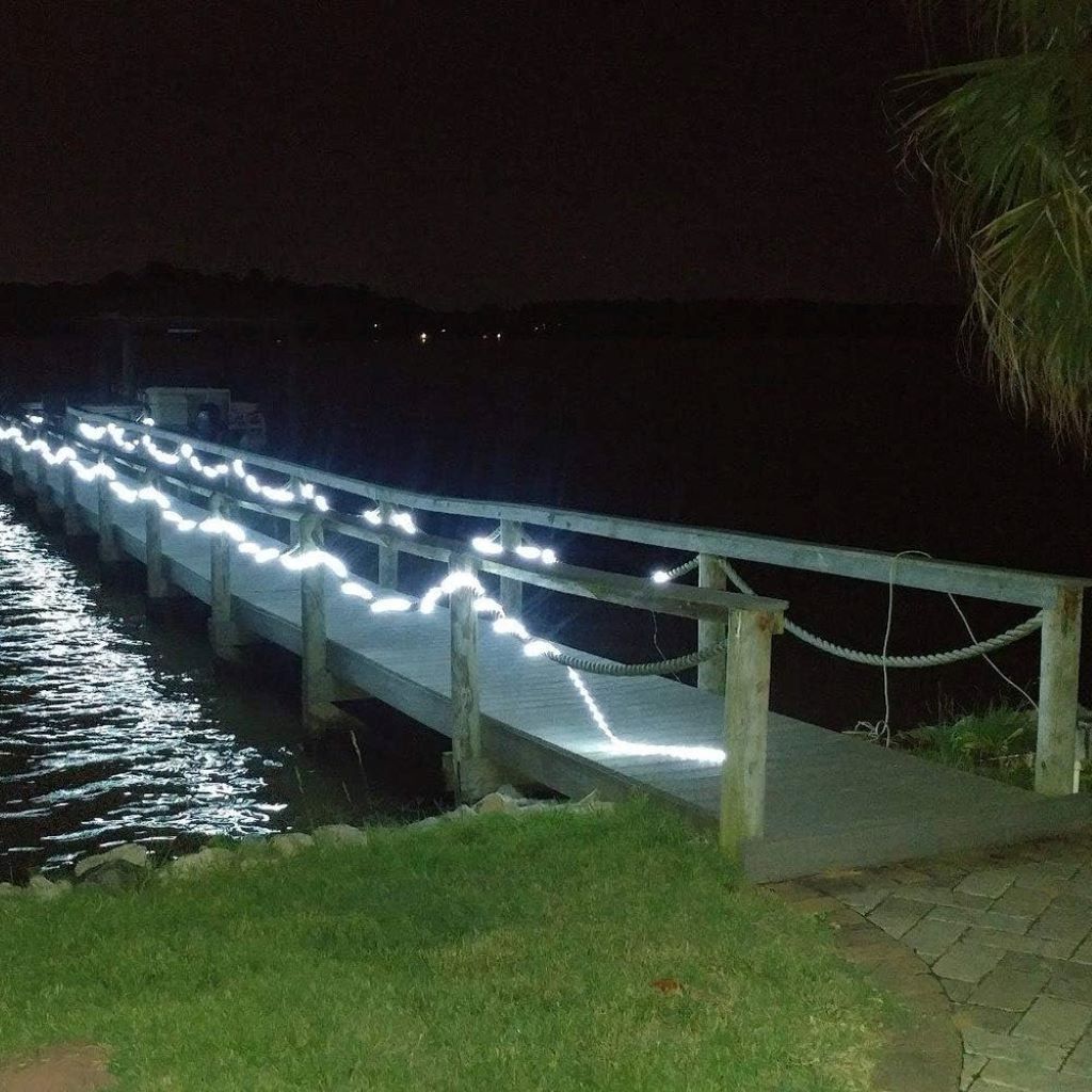 White LED rope lights from DINGFU glowing along a backyard fence, showcasing weatherproof build for outdoor ambiance.