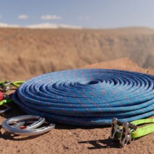 Climber scaling granite face with dynamic kernmantle rope, highlighting braided sheath and vibrant color stripe