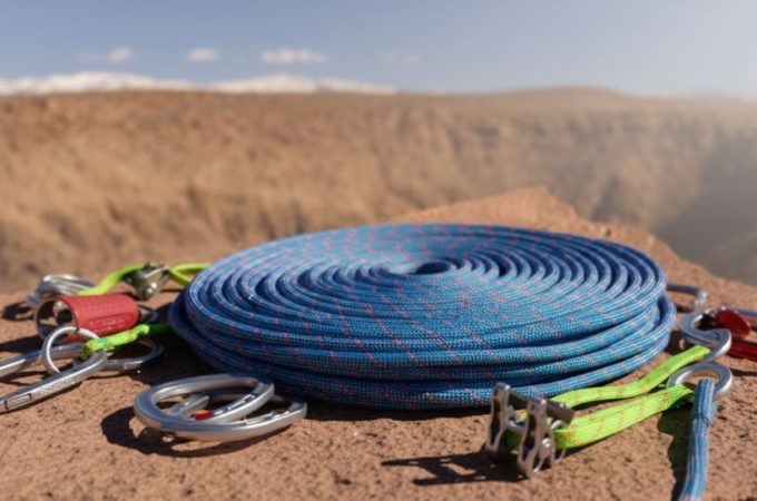 Climber scaling granite face with dynamic kernmantle rope, highlighting braided sheath and vibrant color stripe