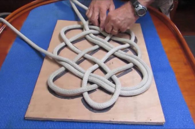 A neatly coiled nautical rope rug in white cotton rests on a hardwood floor, showcasing coastal charm