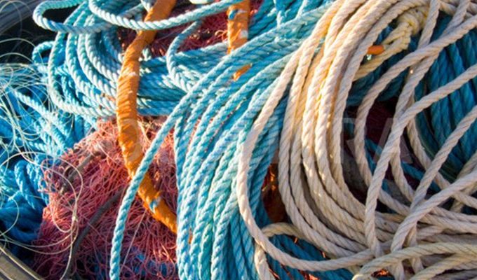Fisherman inspecting fishing ropes on a dock to ensure strength and reliability.