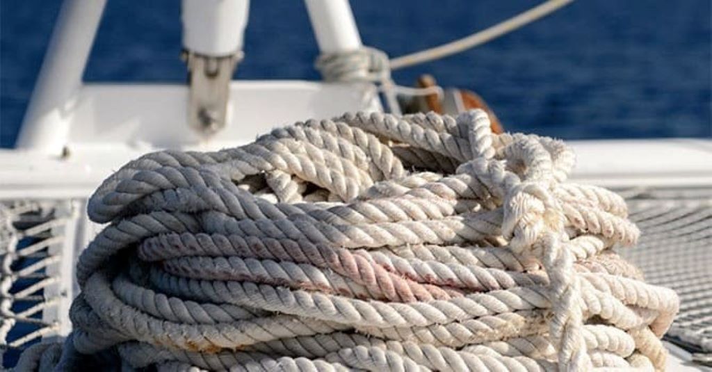 Close-up of marine ropes on a trawler deck being cleaned and checked for wear.