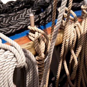 Close-up of a sailor inspecting and caring for strong, durable ropes.