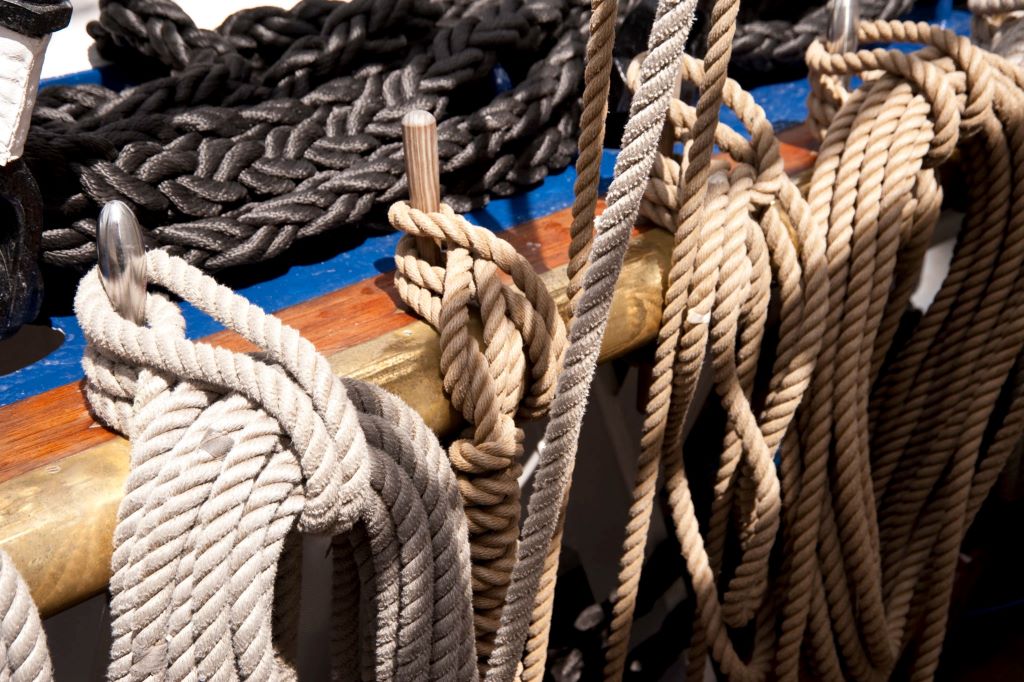 Close-up of a sailor inspecting and caring for strong, durable ropes.