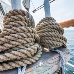 Mariner inspecting ship ropes to ensure durability and safety at sea.