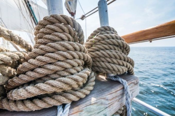 Mariner inspecting ship ropes to ensure durability and safety at sea.