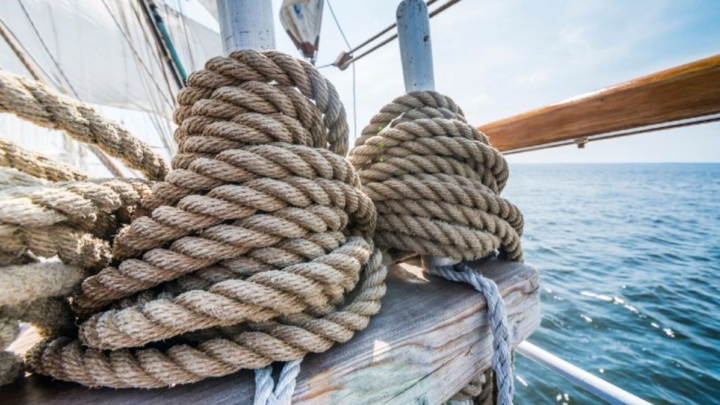 Mariner inspecting ship ropes to ensure durability and safety at sea.