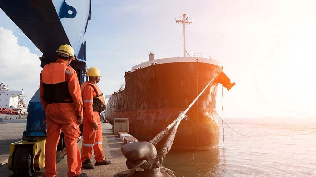 Seafarer inspecting stressed ropes for signs of damage on deck.