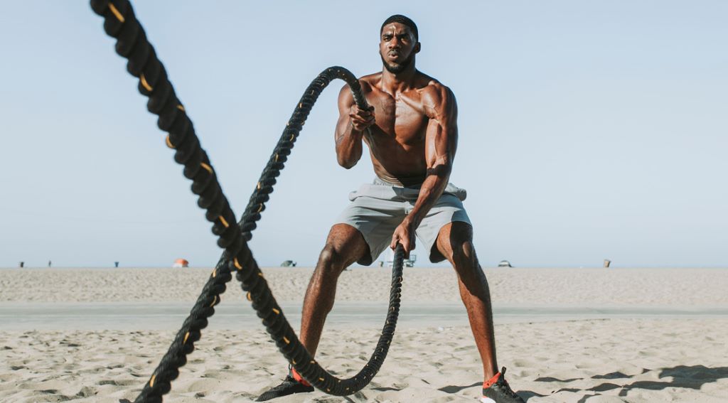 Athlete using battle ropes for a full-body workout in a gym