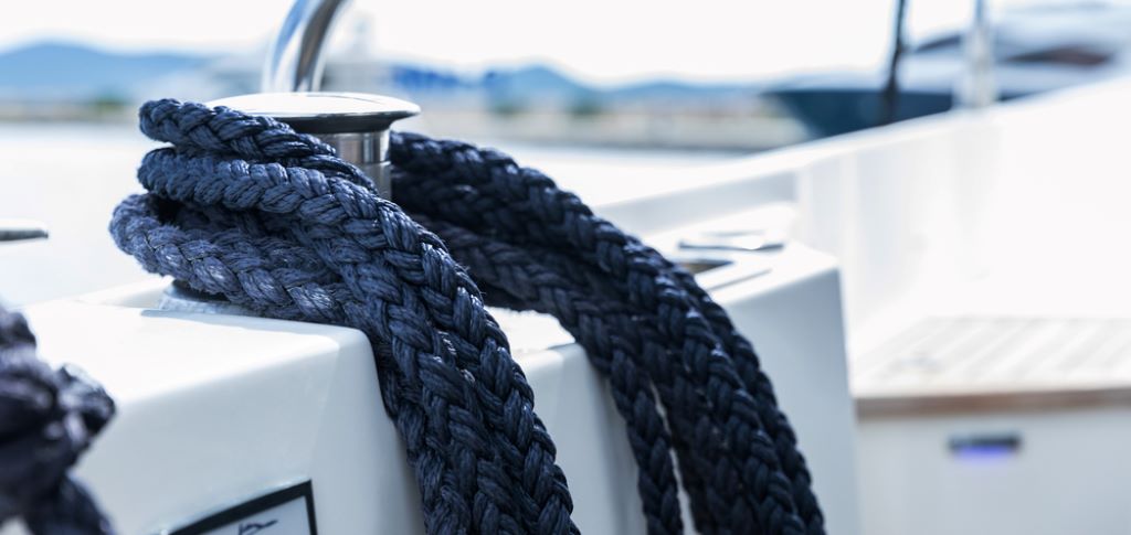 Boater selecting strong rope for boat anchor setup on a dock before sailing