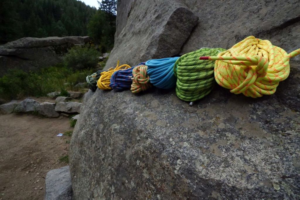 Adventure climber securing a high-strength rope before rappelling down a cliff face