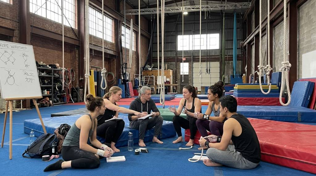 Group of circus artists sharing notes during a rope workshop
